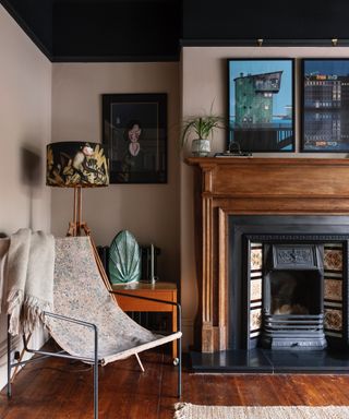 colors that go with brown, living room with taupe walls, wooden floorboards, wood fire surround, side table, retro chair, black ceiling, artwork, retro feel