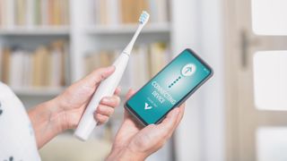 A smart toothbrush next to a phone showing its app