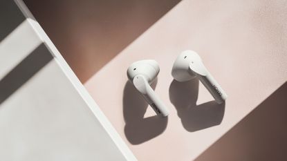 Denon AH-C500W in white on a pastel coloured background