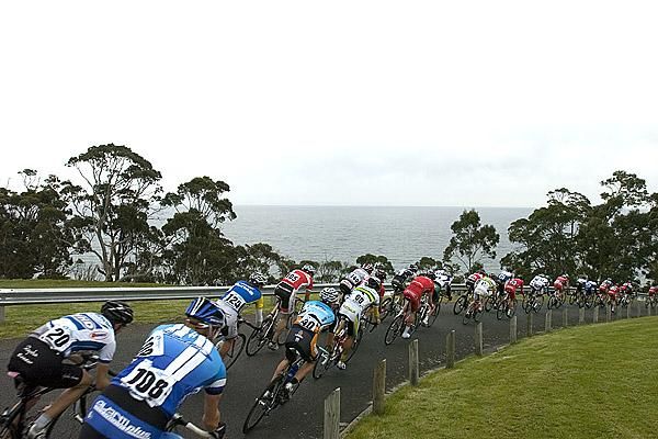 The peloton descend around the course with Bass Strait in the background.