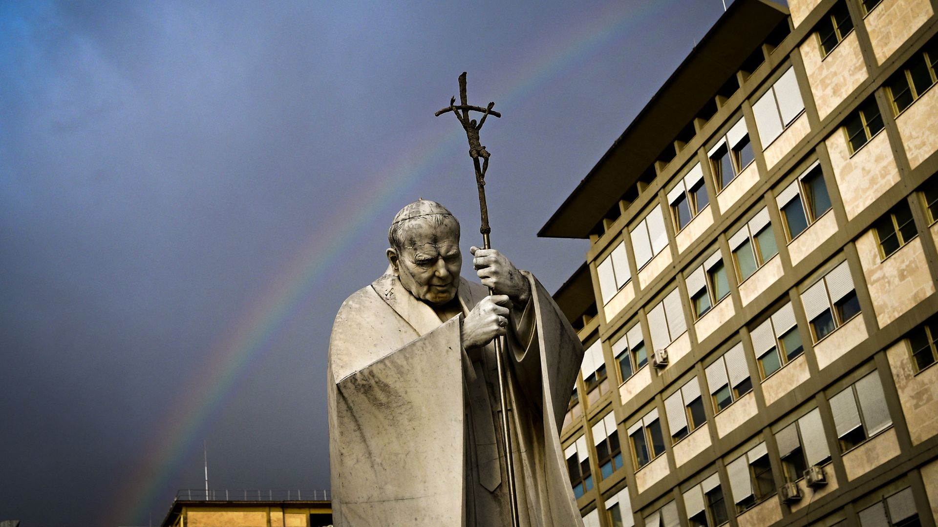 
                                A rainbow appears over a statue of Pope John Paul II outside the hospital where Pope Francis is hospitalized in Rome
                            