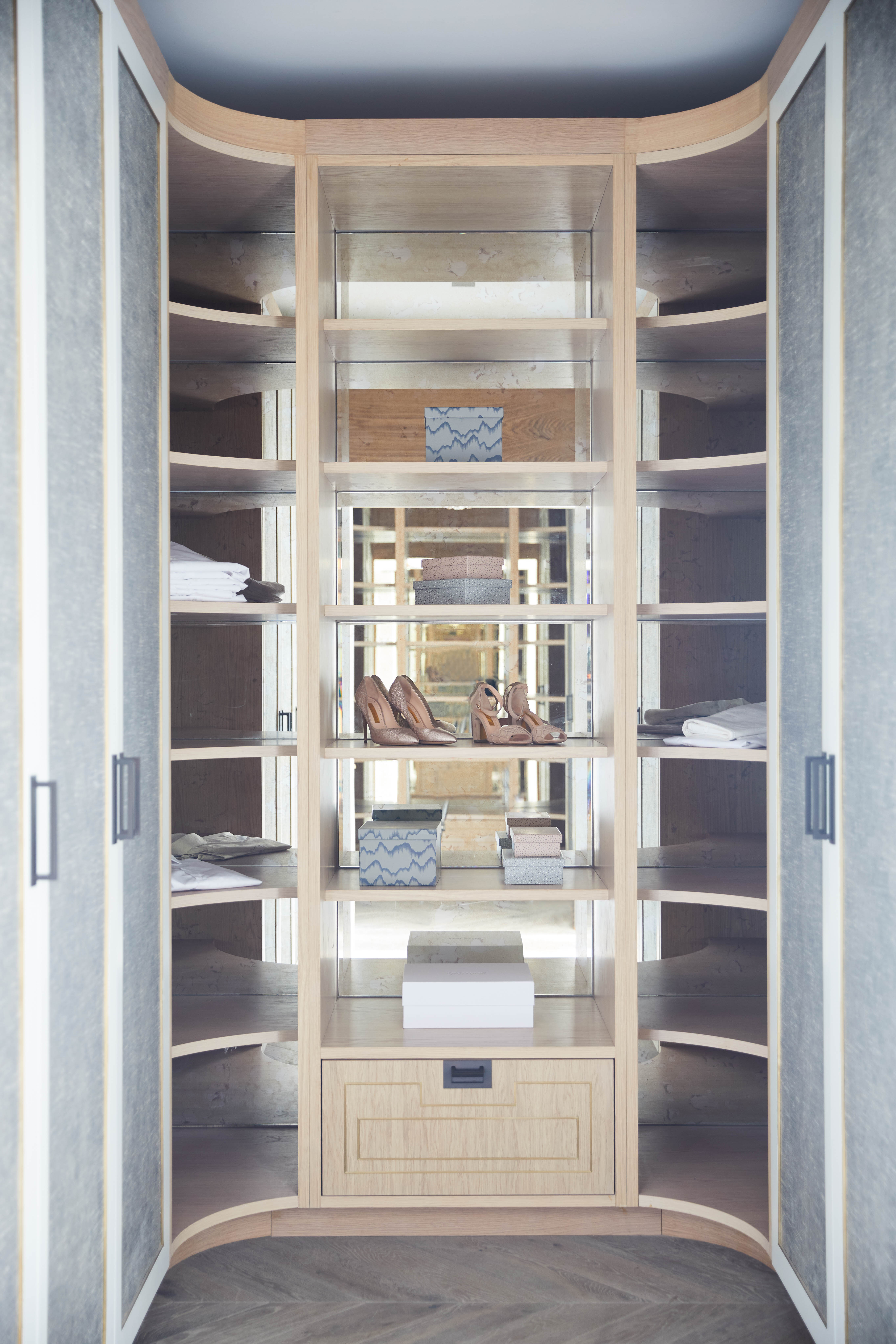 small walk-in wardrobe/closet with mirror backing in shelves