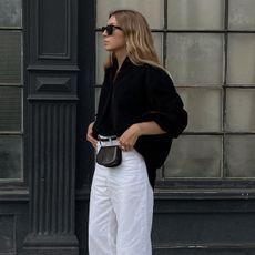 Brittany Bathgate wearing a black button-down shirt and white trousers.