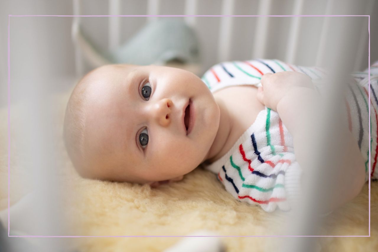 A baby looking through the bars of a cot