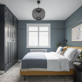Blue bedroom with blue fitted wardrobes and yellow velvet bedframe