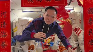 astronauts in blue flight suits pose among bright red and gold decorations with the Chinese character 'fu', or 'fortune' on them