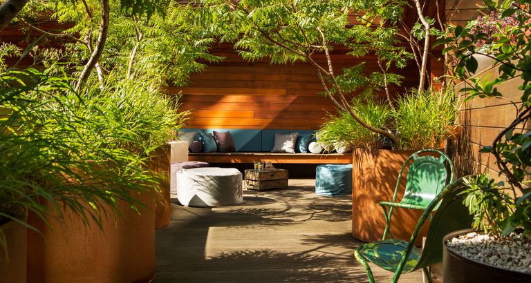 An example of backyard ideas showing a turquoise bench seat against a wooden wall surrounded by greenery