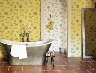 bathroom with yellow botanical wallpaper with a silver metallic freestanding roll top bath