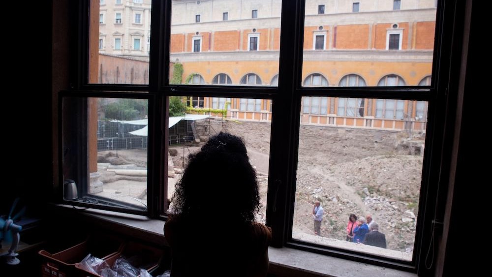 A person in a window overlooks an excavation site in Rome.