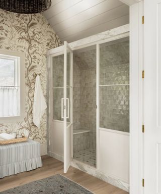 Wallpapered bathroom with tiled shower and upholstered bench