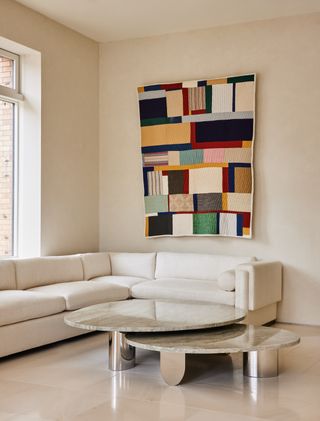 White sofa and metal coffee table with colourful patchwork artwork on the wall
