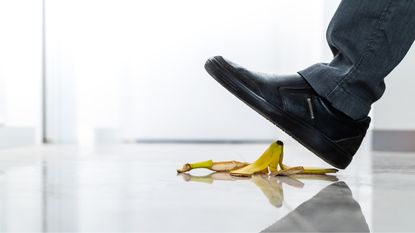 A businessman's foot about to step on a banana peel.