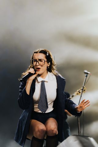 gracie lawrence wears a tie and jacket while performing on stage with her band lawrence