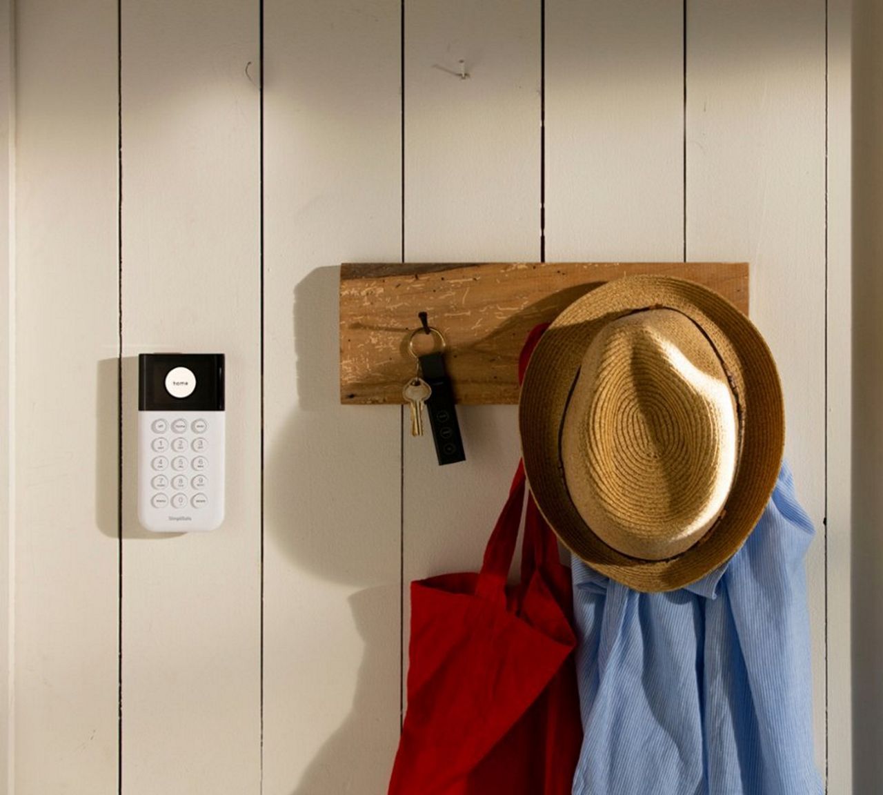 a Simplisafe key fob remoten on a paneled wall