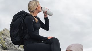 A hiker stops for a drink of water