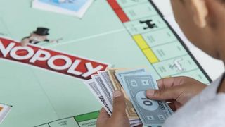 Player counting money in front of a monopoly board