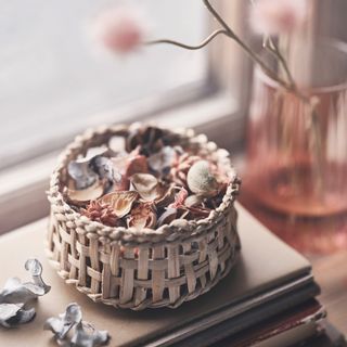 pot full of pot-pourri on top of a book on a side table
