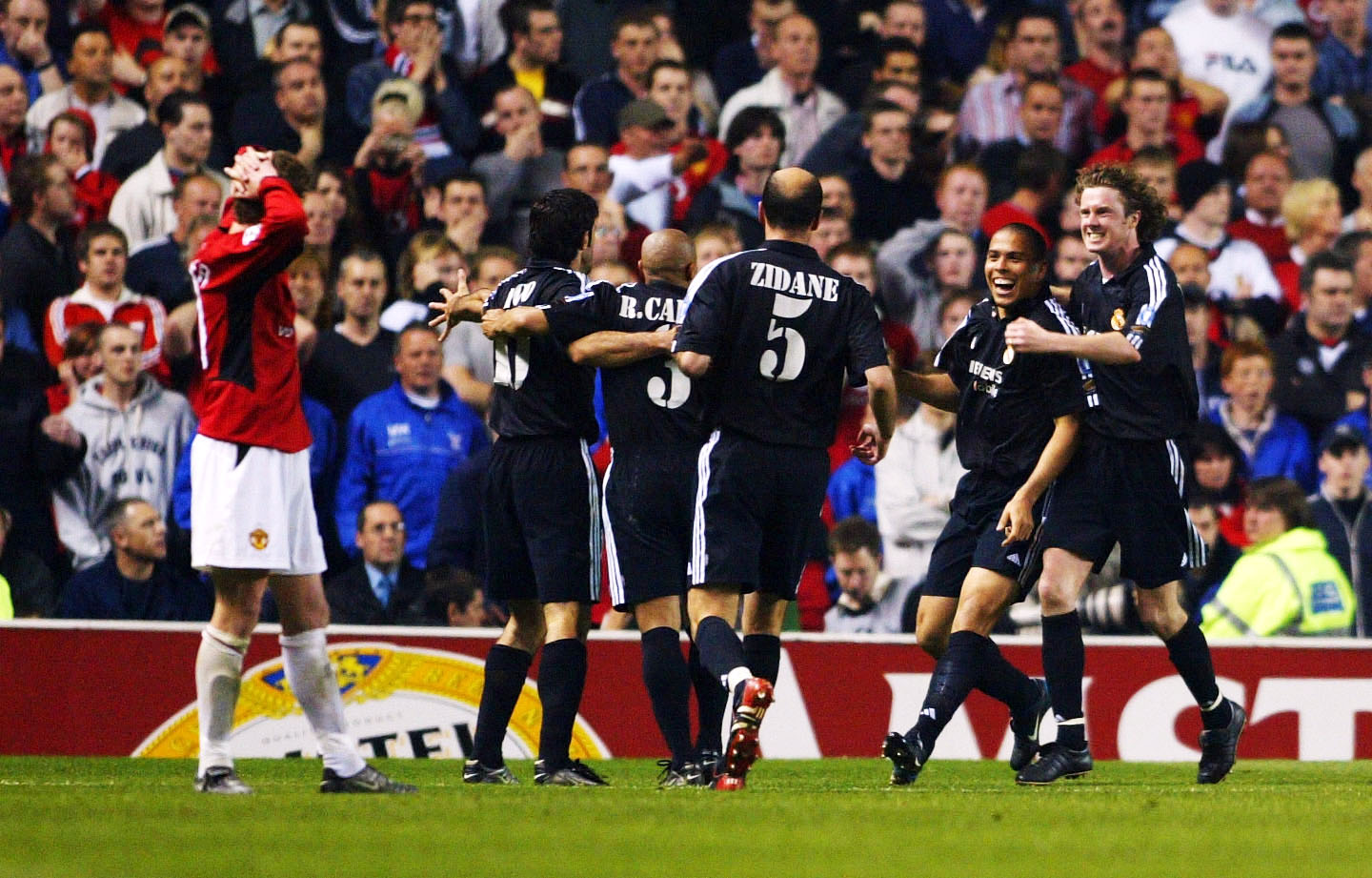 Ronaldo riceve i complimenti dai suoi compagni di squadra del Real Madrid dopo aver segnato una tripletta contro il Manchester United all'Old Trafford nell'aprile 2003 mentre Ole Gunnar Solskjaer gli tiene la testa.