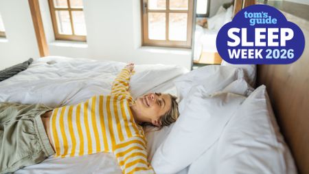 A woman lies on her back on her mattress on a sunny spring day, with a big smile on her face. In the top right corner is a Tom's GUide Sleep Week 2026 graphic