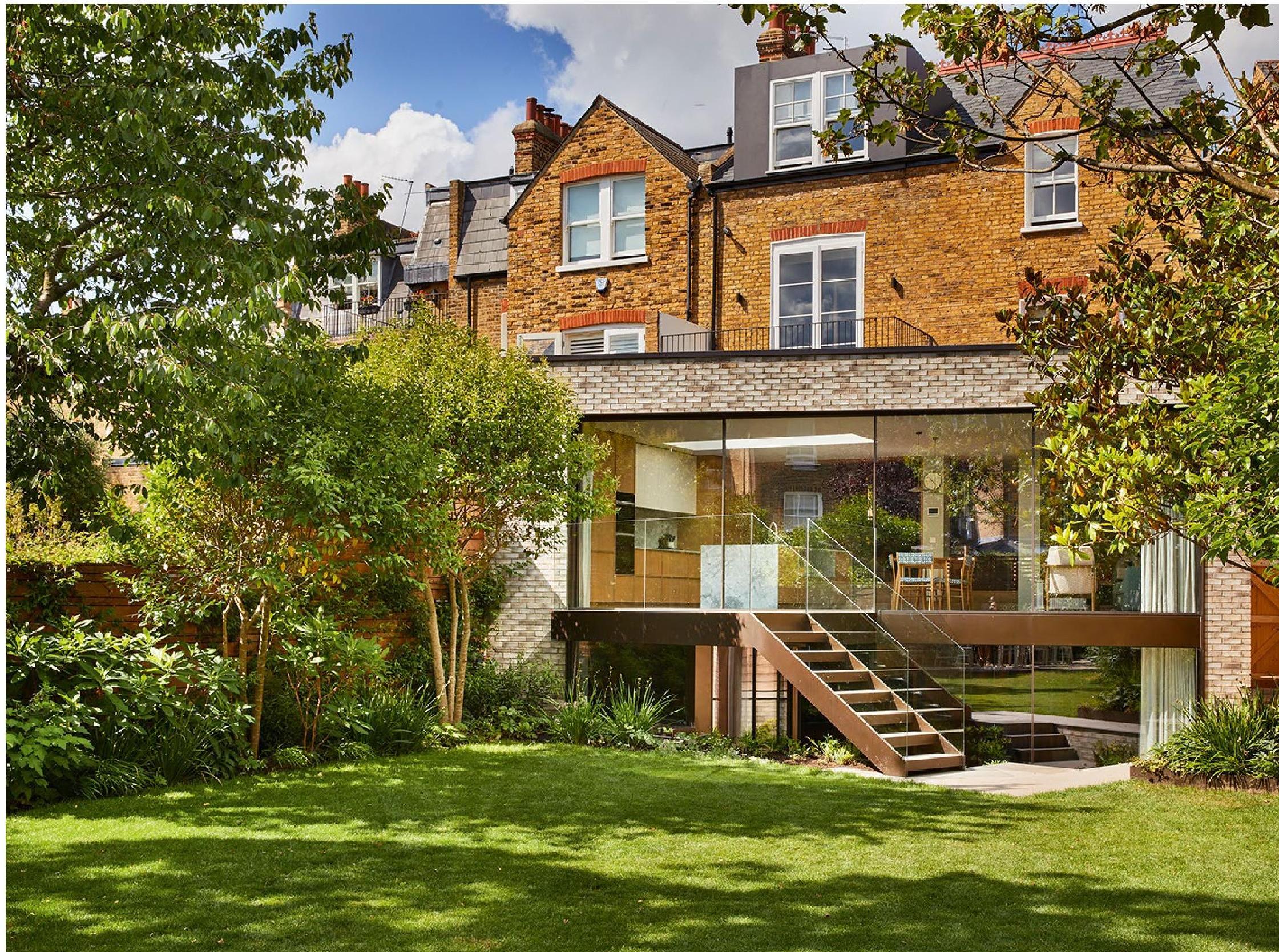 A modern brick extension at the rear of a semi-detached Victorian house, showcasing a blend of traditional and contemporary architecture in a lush garden setting.