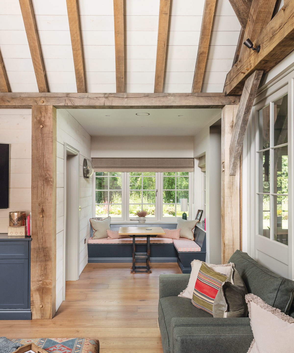 living room with L-shaped bench under the window and wooden beamed ceiling