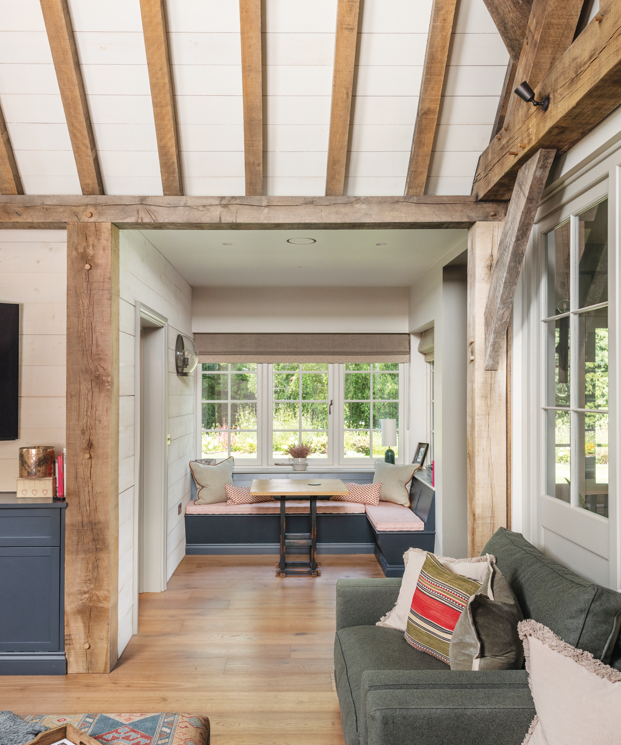 living room with L-shaped bench under the window and wooden beamed ceiling