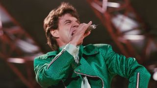 Mick Jagger singing, wearing a green jacket