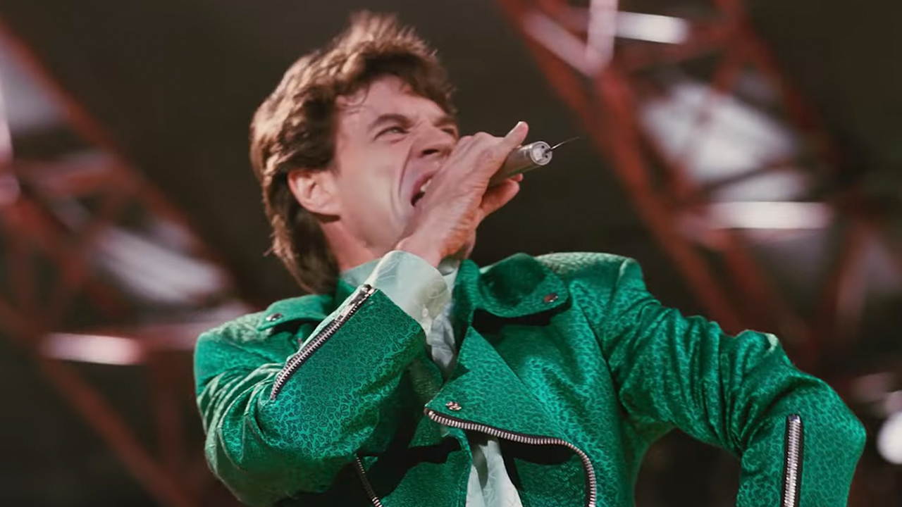 Mick Jagger singing, wearing a green jacket