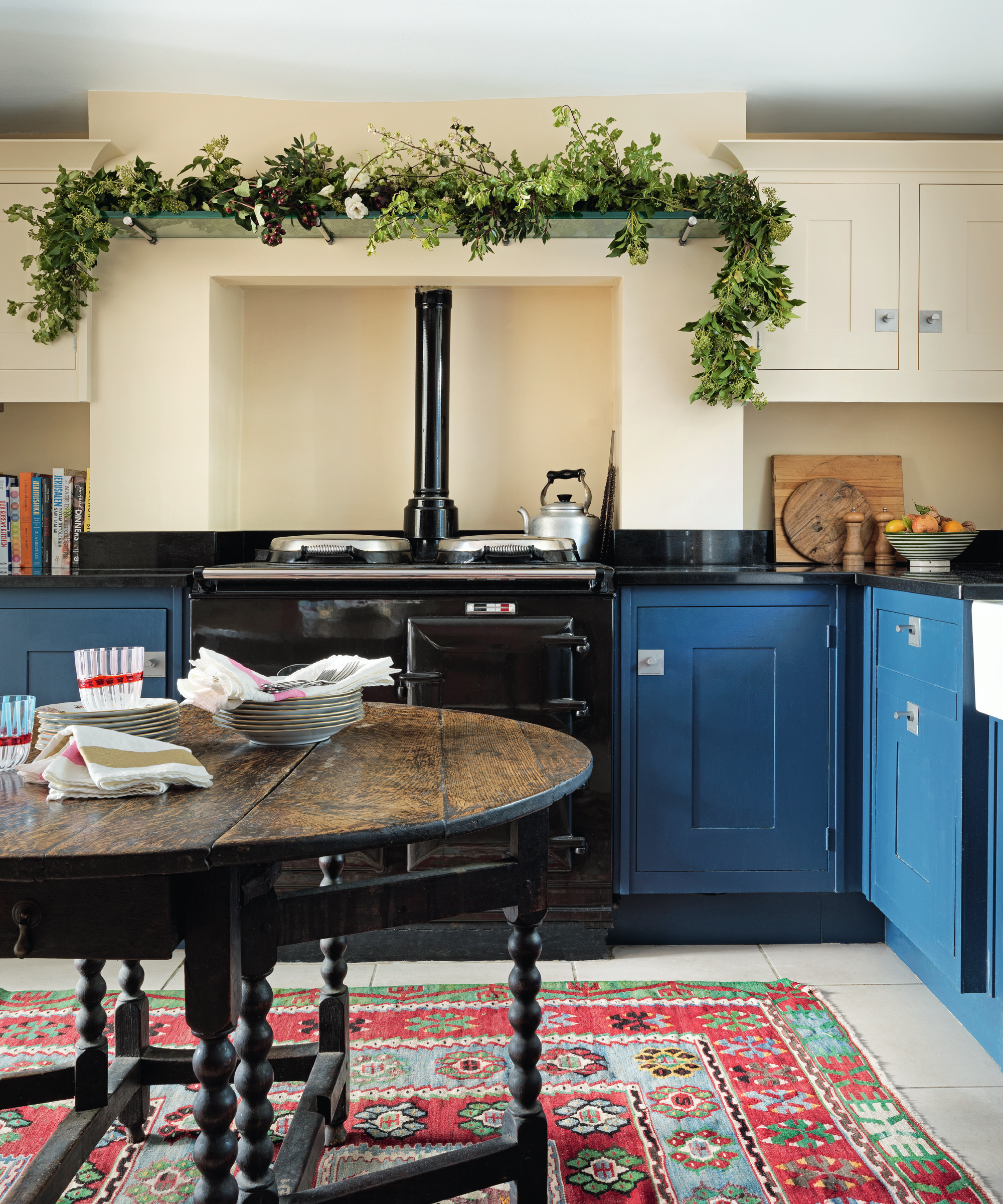 Kitchen color ideas in a blue and cream colour block kitchen with a red patterned rug.