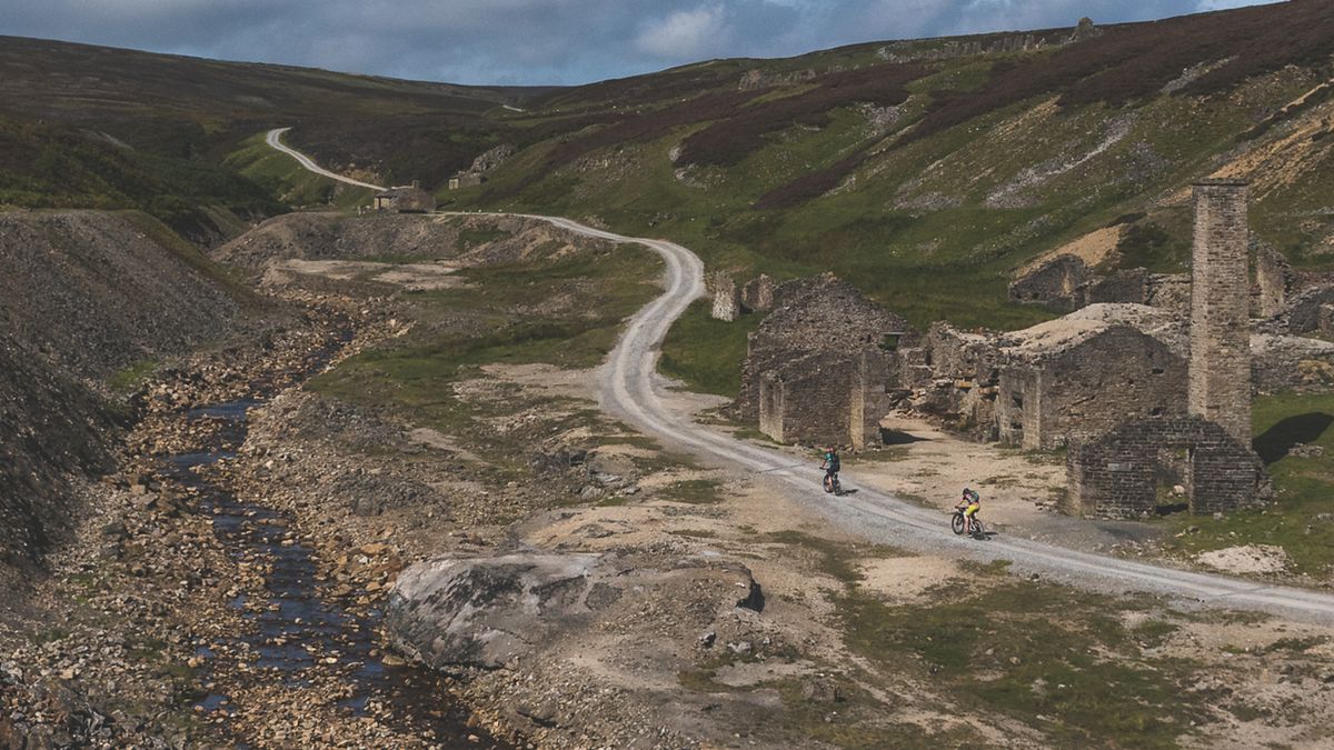 Two gravel riders climbing past Old Gang Smelt Mill