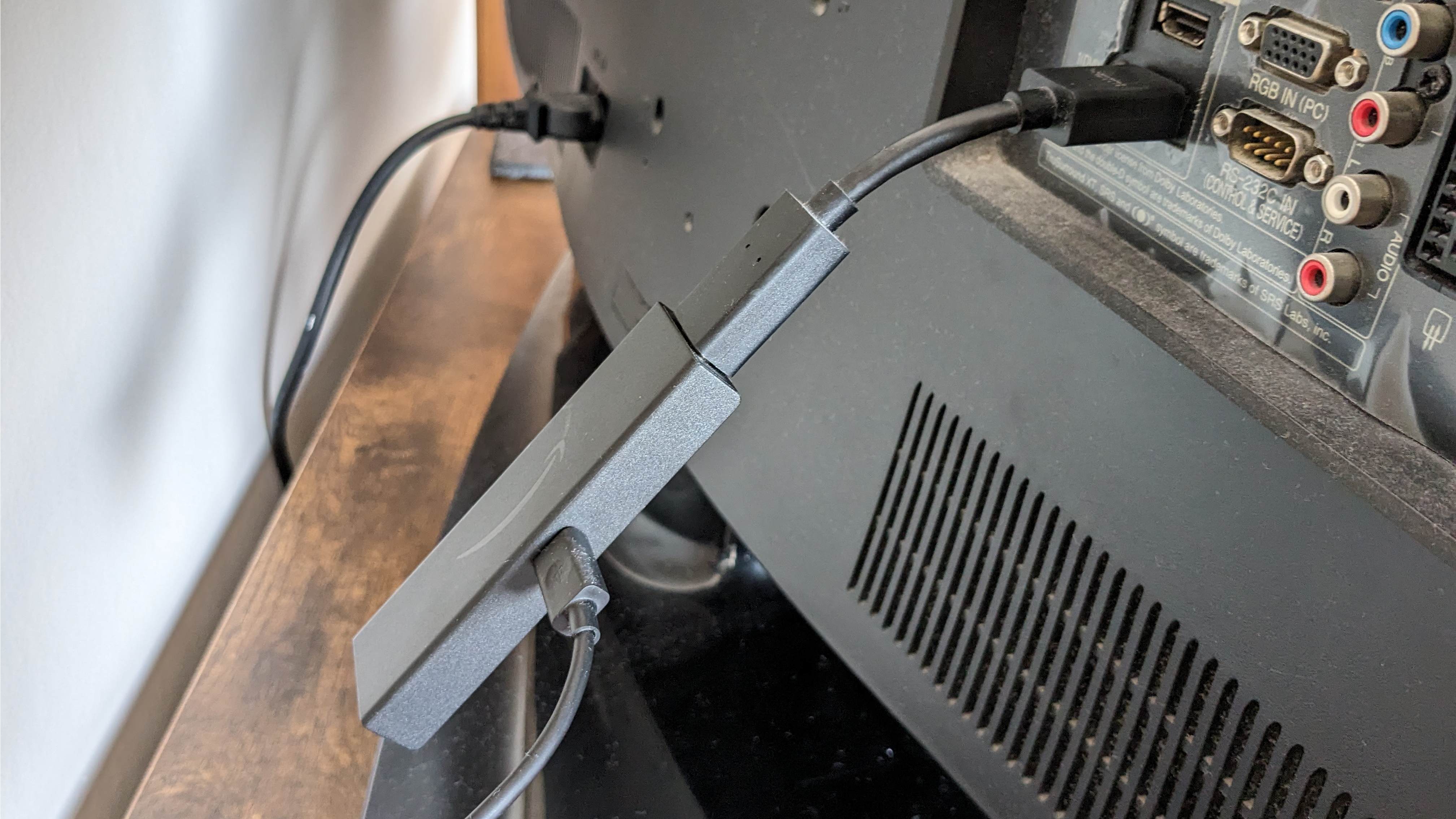 An Amazon Fire TV Stick 4K plugged into its HDMI extended plugged in the back of a TV.