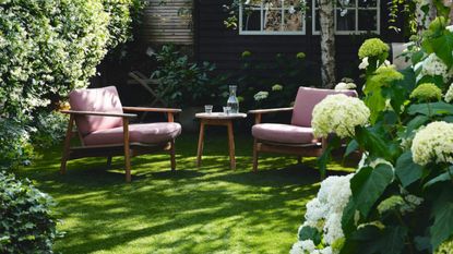  Seating area in the garden surrounded by trees and flowerbeds with white and green hydrangeas. Interior designer Susan Hoodless and Erskine Berry's renovated four storey terraced west London home.