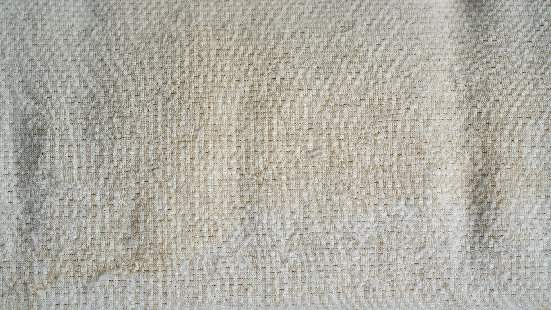 A close up of yellow stains from sweat on bedding