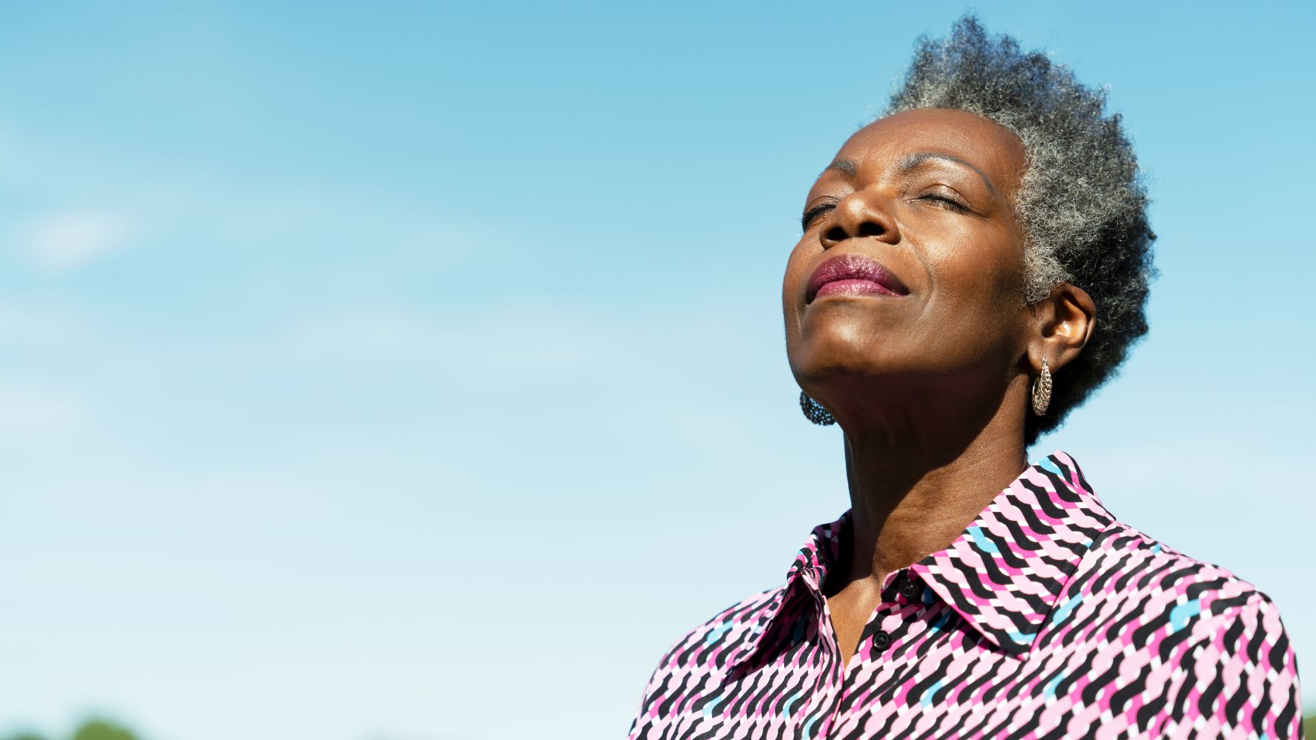 A smiling mature woman basks in the morning sunlight.