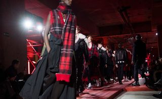 A group of male models on the cat walk modelling tartan style clothing by Alexander McQueen.