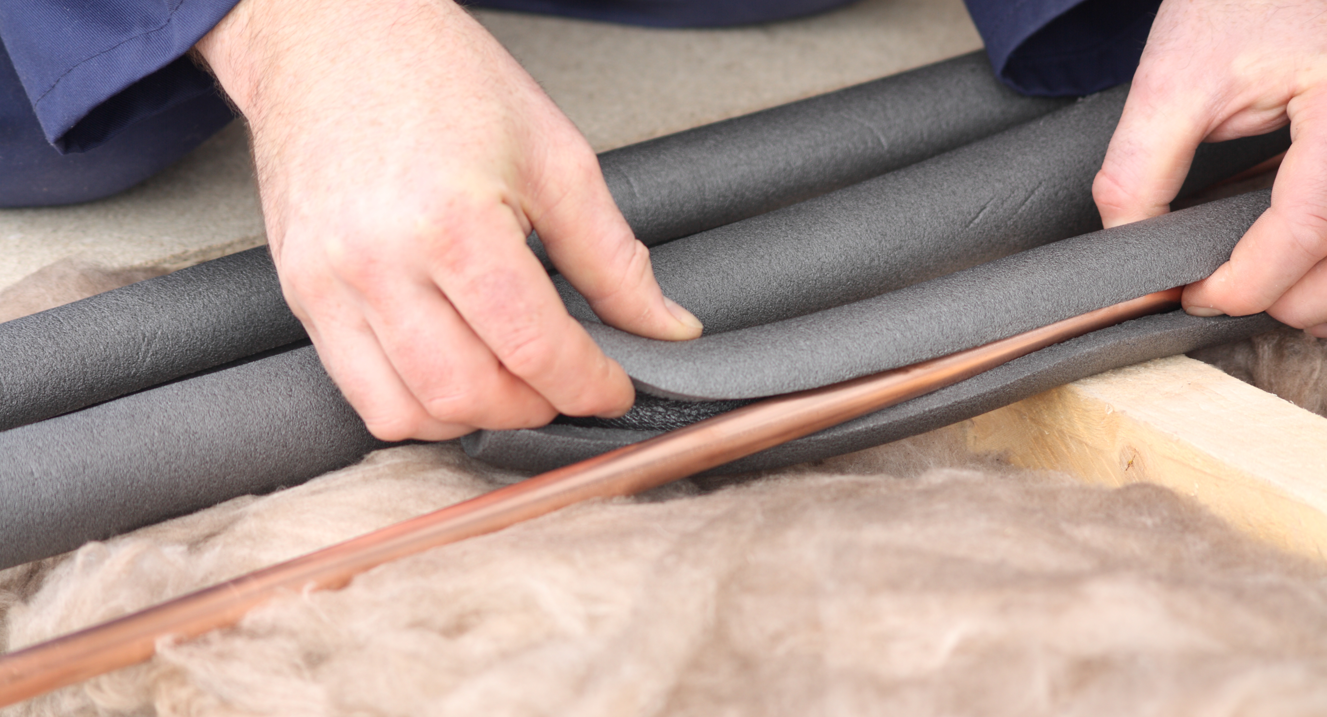 Hands hold an insulation wrap to cover pipes.