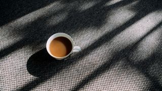 a cup of coffee in a white mug on a gray carpet
