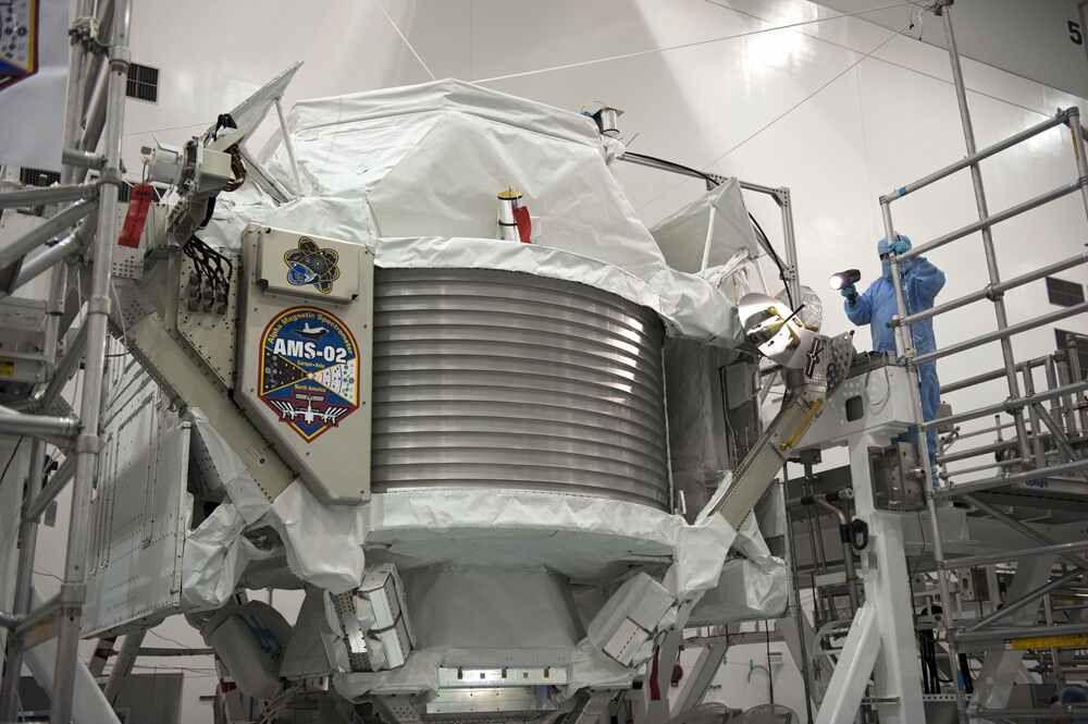 Technicians examine the $2 billion Alpha Magnetic Spectrometer instrument in a work stand ahead of its planned launch on NASA&#039;s space shuttle Endeavour. The AMS instrument will search for cosmic rays from the International Space Station.