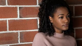 Alise Willis as Meg in Echoes stood against a red brick wall