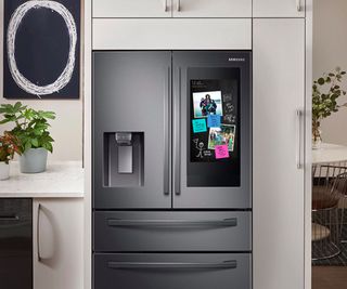 Samsung smart refrigerator in a home with white cabinets behind it