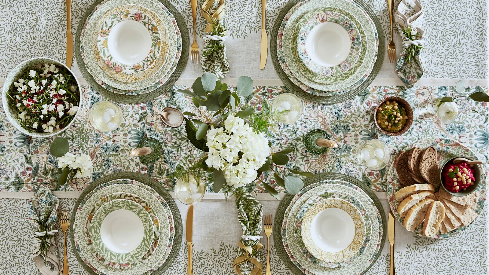Tablescape with green William Morris print tablecloth, matching charger plats, gold flatware and white floral arrangements