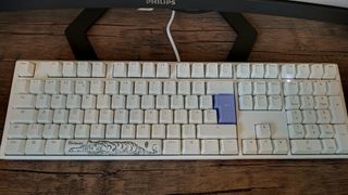 A white Ducky One 3 mechanical keyboard on a wooden desk.