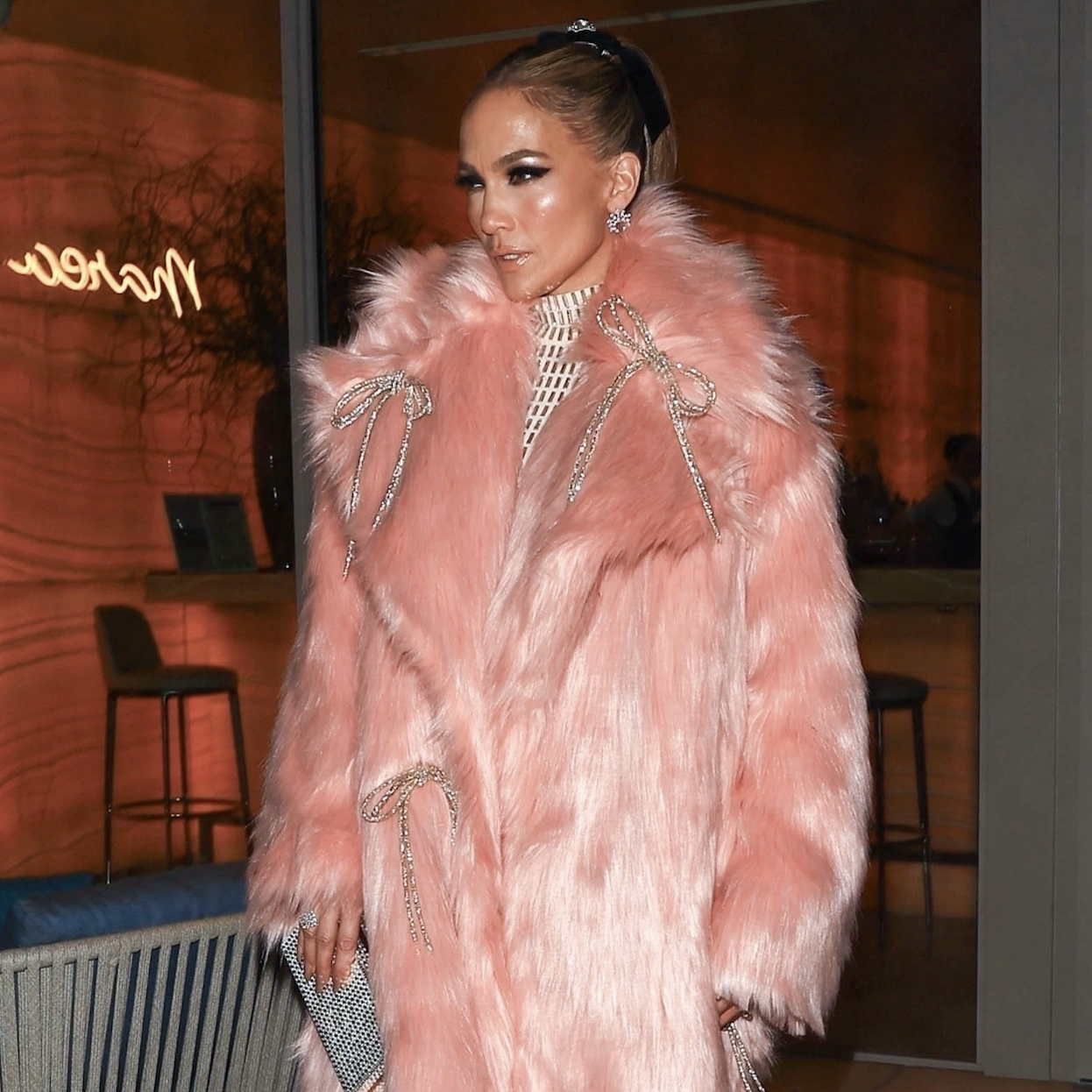 Jennifer Lopez looks pretty in pink as she steps out in a flirty, mid-length pink fur coat adorned with silver bows, layered over a white floor-length turtleneck gown, and finished off with heels and a chic bag, while leaving dinner in Beverly Hills after the GRAMMYs.