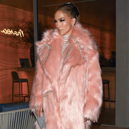 Jennifer Lopez looks pretty in pink as she steps out in a flirty, mid-length pink fur coat adorned with silver bows, layered over a white floor-length turtleneck gown, and finished off with heels and a chic bag, while leaving dinner in Beverly Hills after the GRAMMYs.