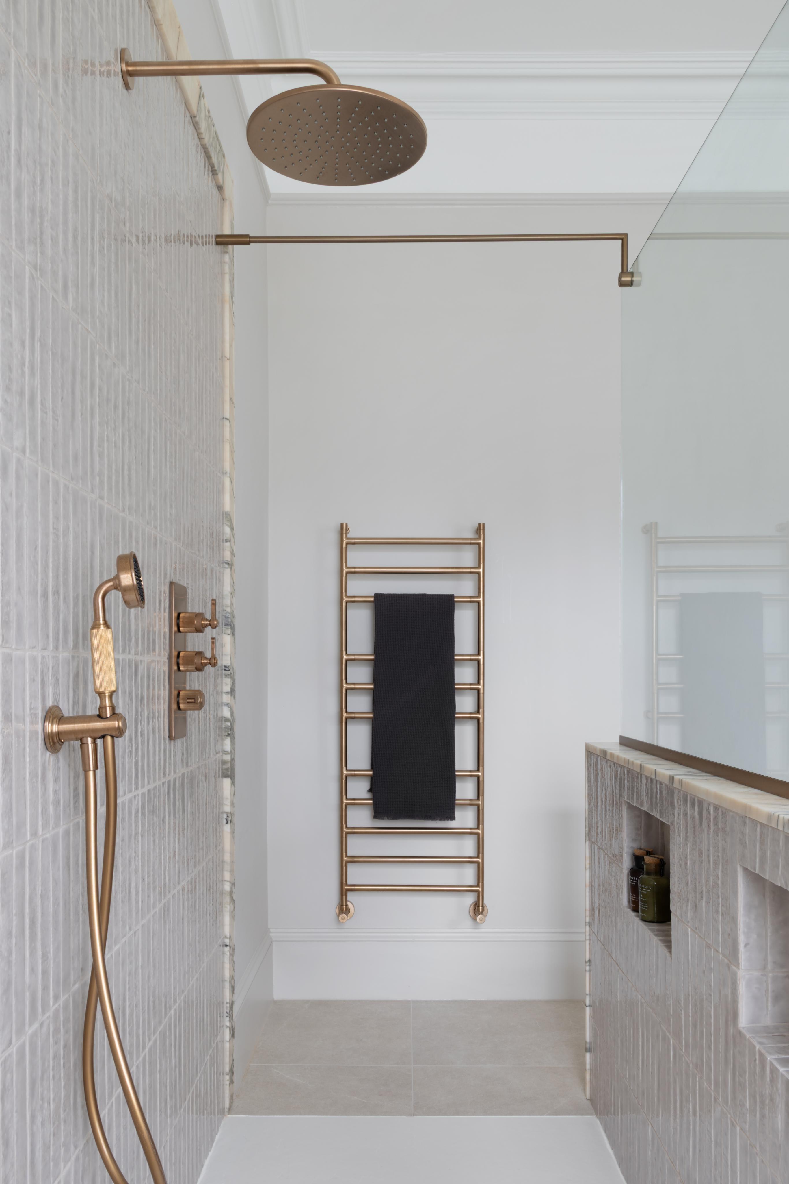 wall-mounted towel rail in antique brass outside of a walk-in shower