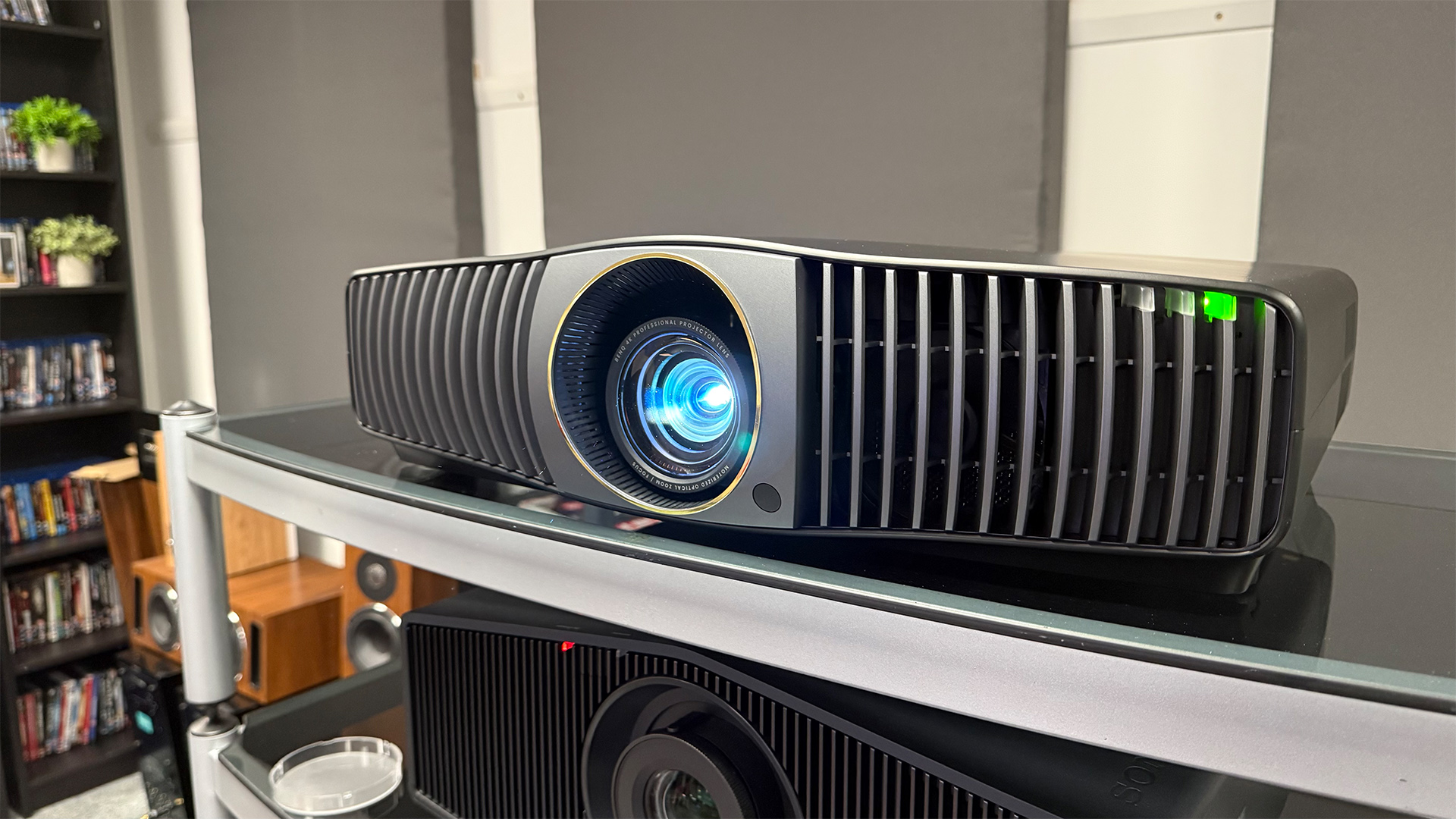 BenQ W5850 home cinema projector on glass AV rack with blue light projecting