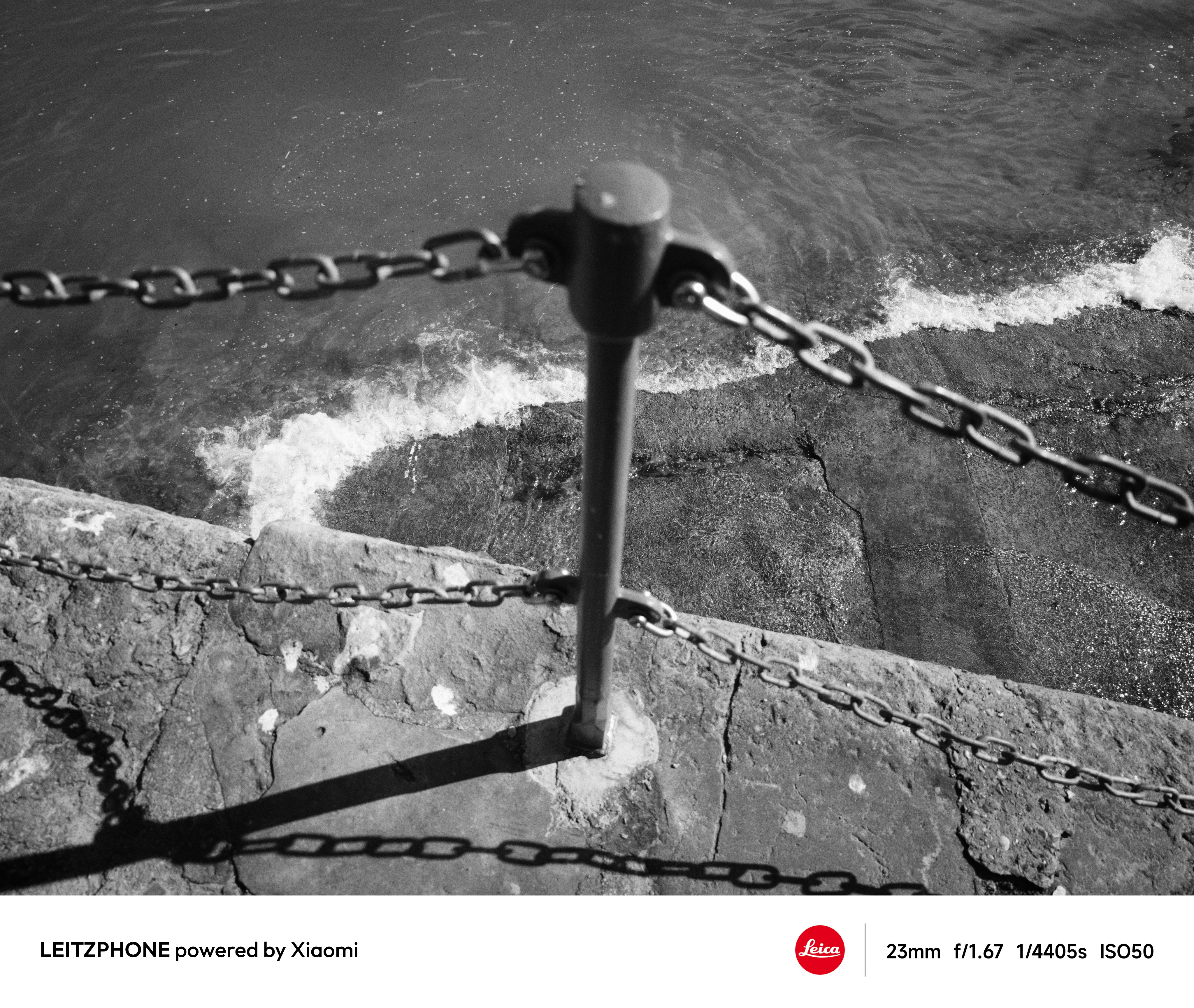 Black-and-white photo of chains above waves on concrete