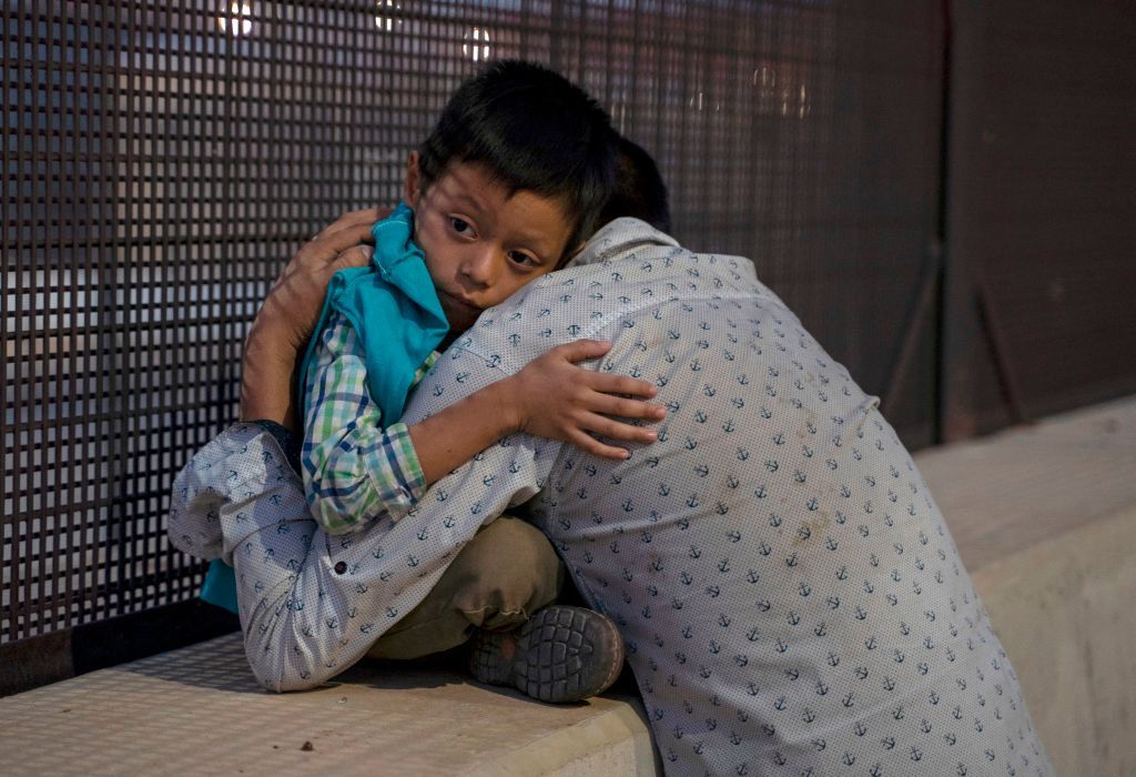 A child hugs his father goodbye after crossing into U.S. in El Paso