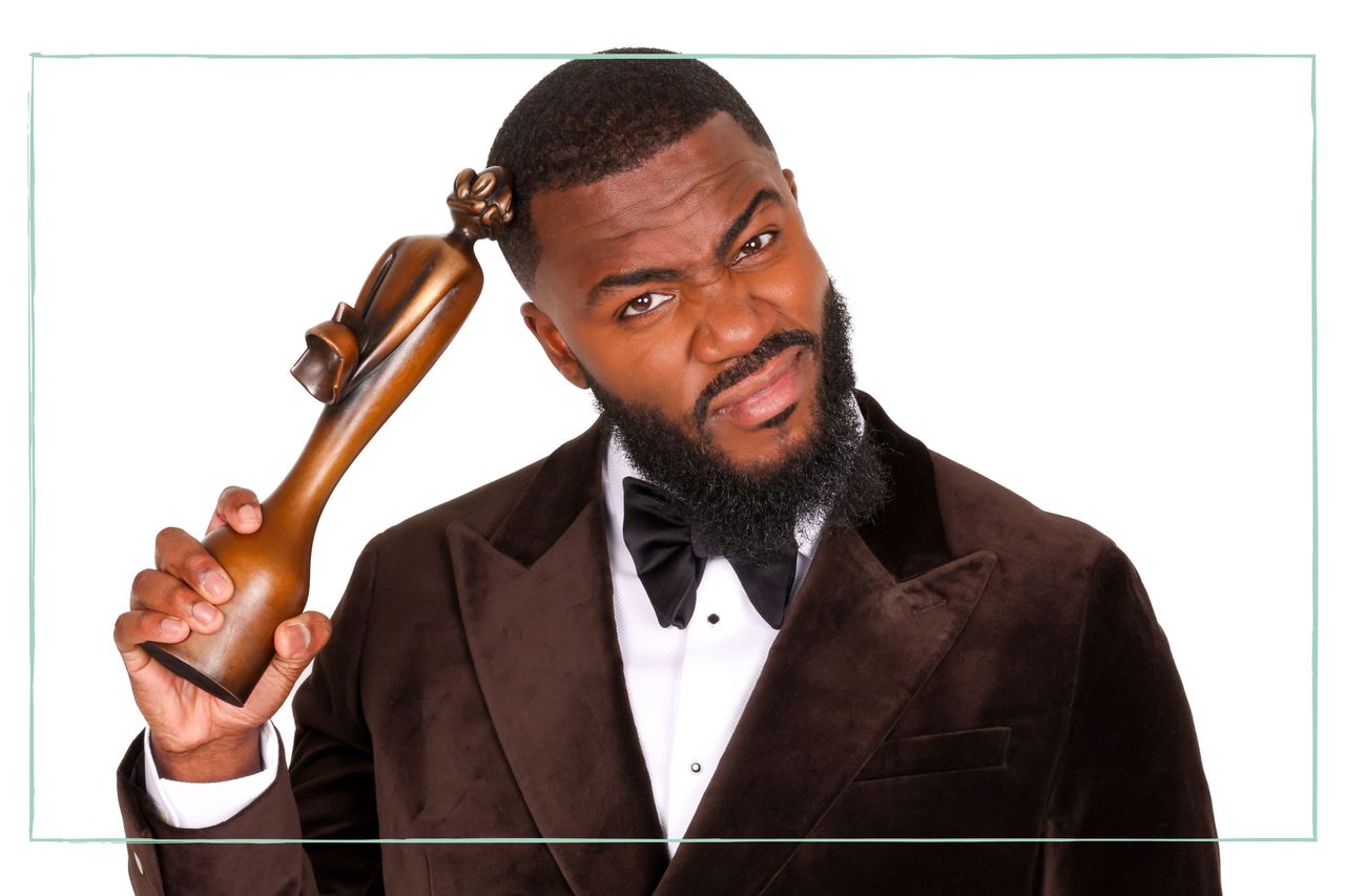 Brit Awards presenter Mo Gilligan in a tuxedo scratching his head with an award