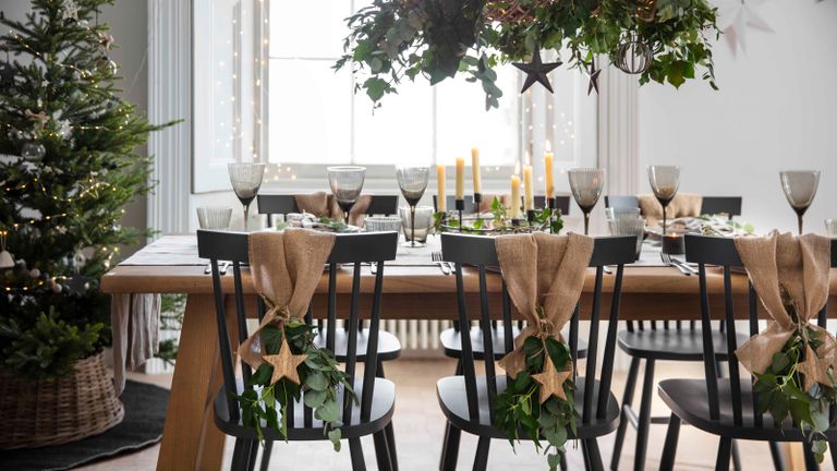 dining table set up for christmas with hanging foliage and candles